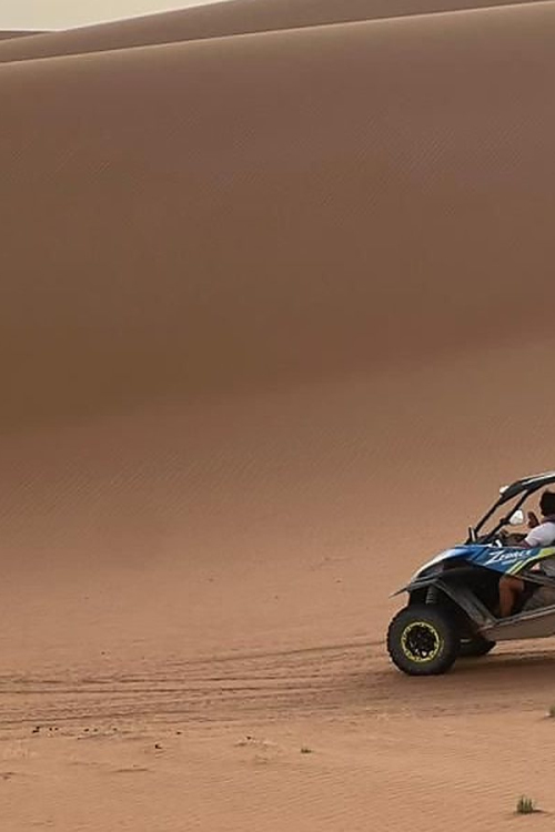 Buggy SSV attaquant la montee d'une grande dune de sable dans le desert marocain